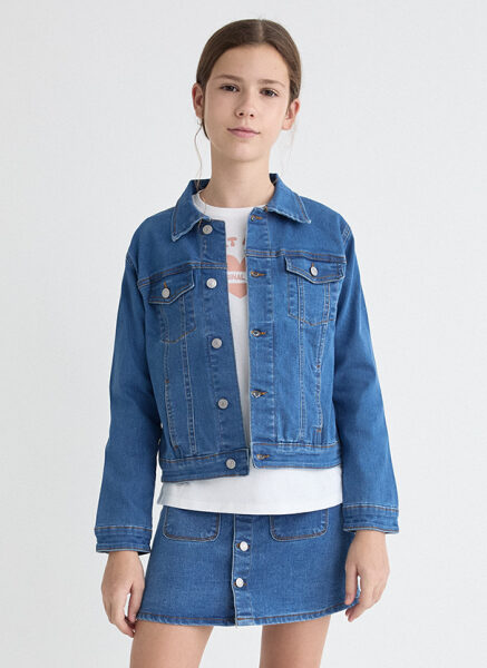 Cazadora en azul denim con cuello camisero y manga larga. Cierre botonadura frontal. Bolsillos de tipo palstrón en pechera con cierre botón