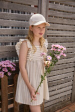 Vestido en tono crudo con finas rayas verticales y volantes en los tirantes, tejido ligero y natural
