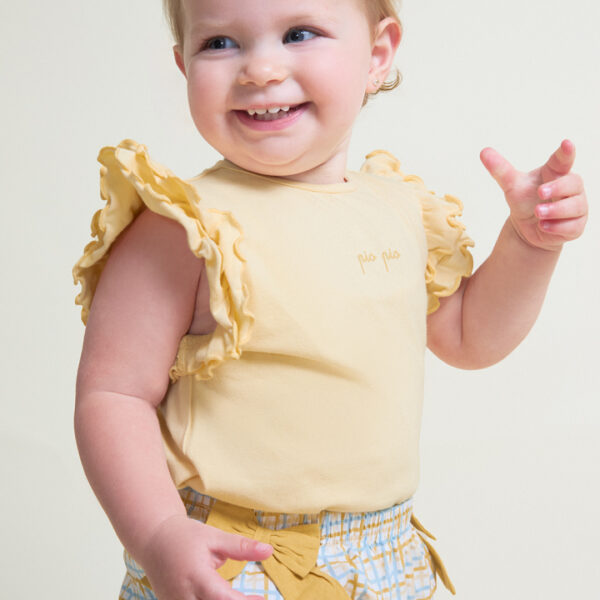 Camiseta sin mangas en color amarillo con detalle de volantes en los hombros y cierre trasero y braguita a juego con estampado de cuadros en tonos amarillo y celeste, decorada con lazos laterales y cintura elástica.