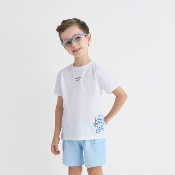 Camiseta blanca de manga corta con detalle frontal “Summer Vibes” y estampado de pulpo con gafas de buceo. Shorts en color azul claro con bolsillos laterales tipo cargo y cintura elástica.