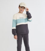 Sudadera en bloques de color crudo, azul verdoso y gris oscuro con detalle bordado “Ski Resort”. Pantalón a juego con cintura elástica y puños ajustados.