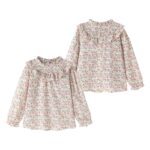 Blusa cuello volante a tono y cierre con botones en la parte trasera.