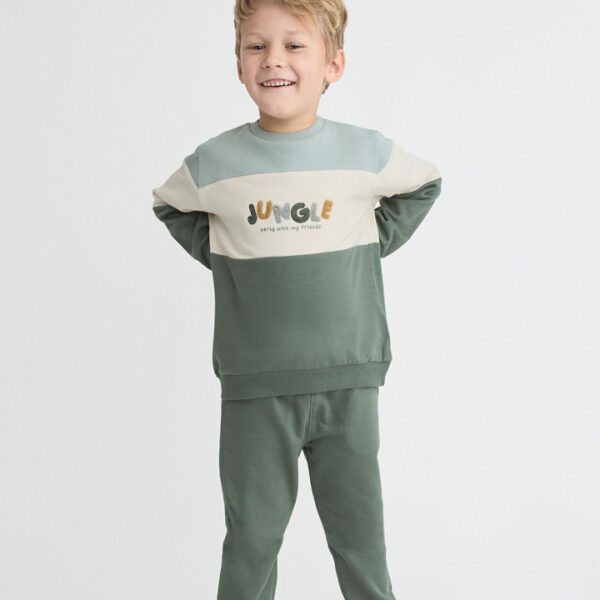 Conjunto de sudadera bicolor tonos verdes y crudo con texto y pantalón verde.